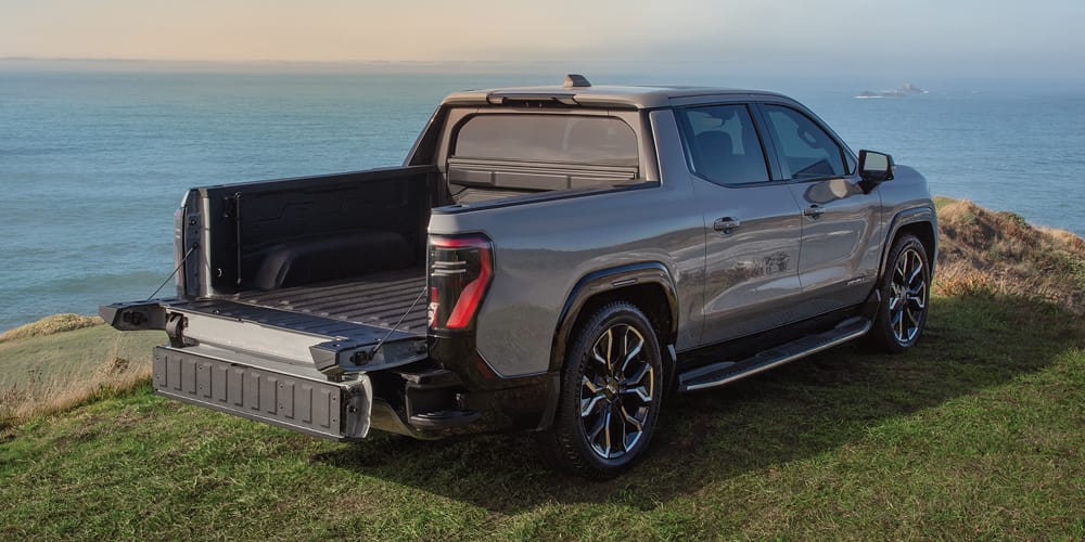 Sierra EV parked on a hill overlooking an ocean with tailgate down